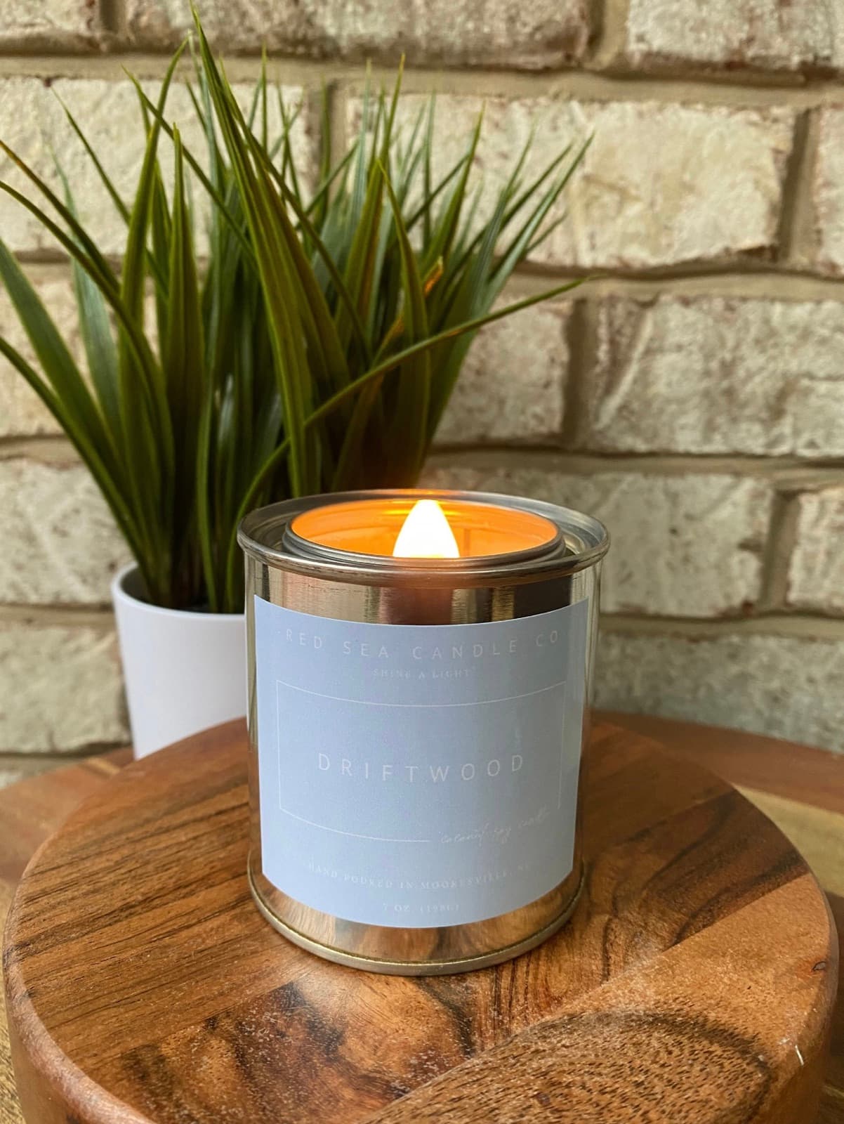 A lit Driftwood candle on a wooden stand