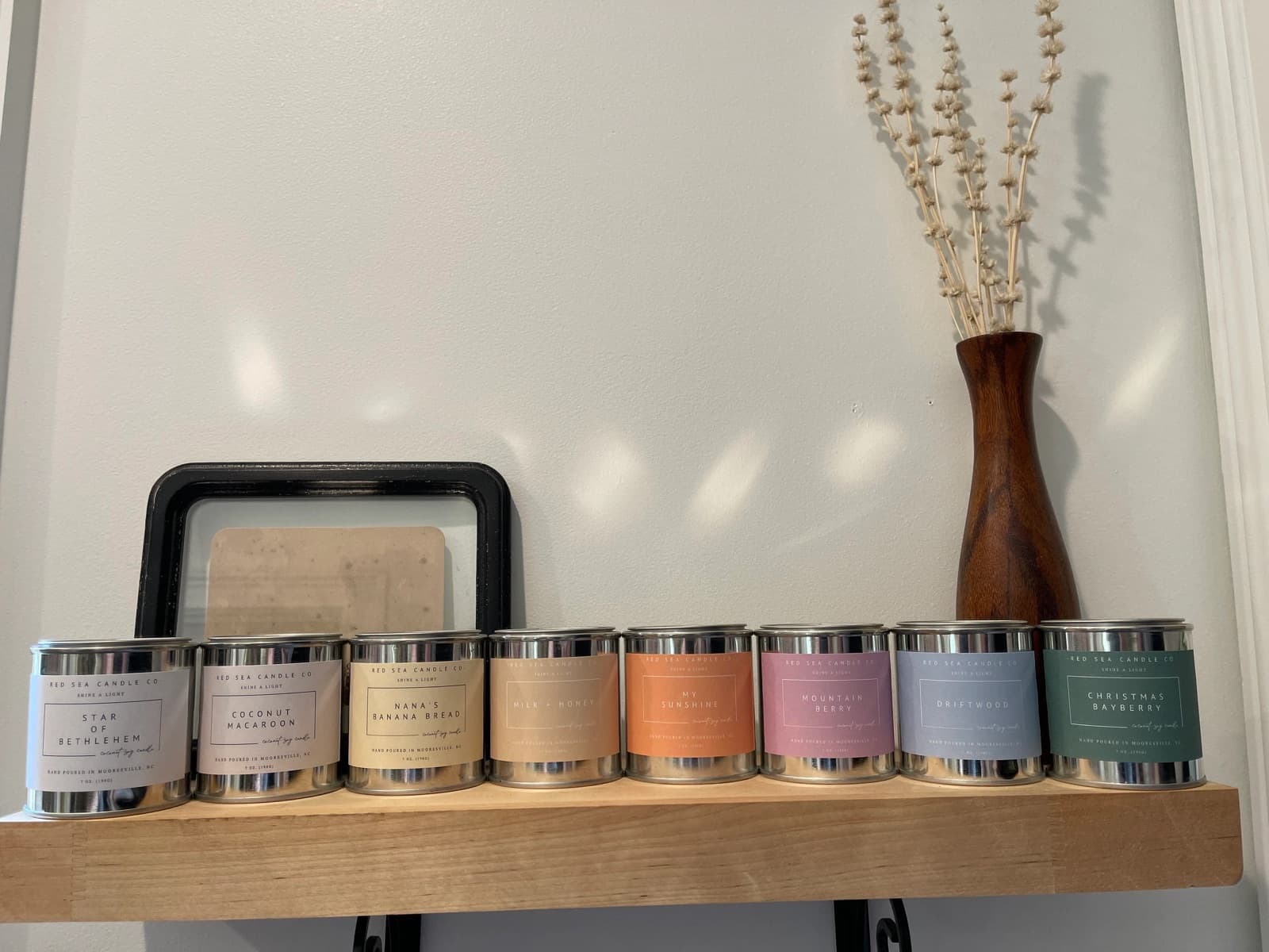 A row of Red Sea Candle Co. candles on a wooden shelf